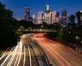 Houston skyline in background with traffic light blurs on highway in foreground. Photo by Trace Hudson: https://www.pexels.com/photo/an-aerial-photography-of-city-buildings-at-night-near-the-road-7142456/