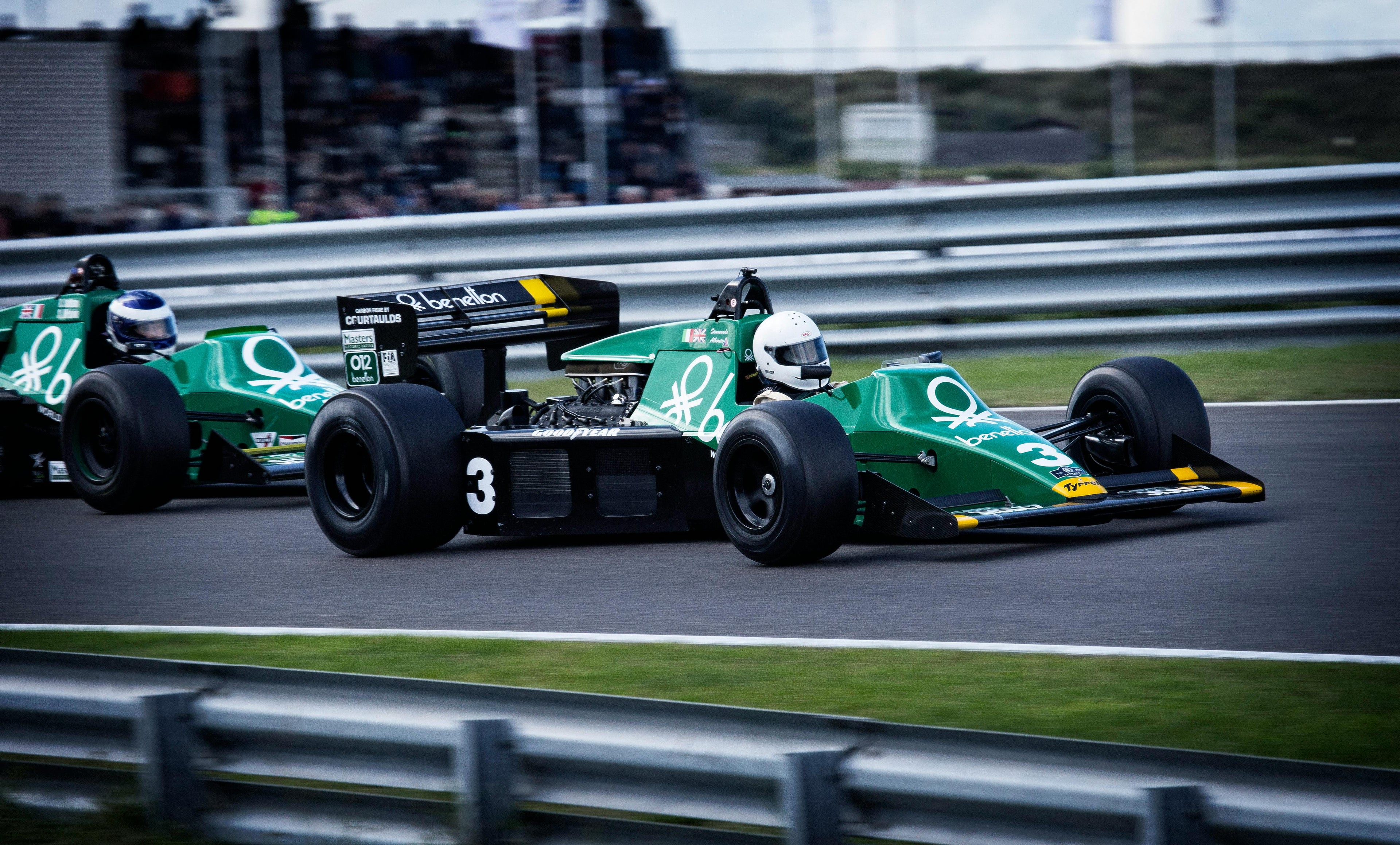 Two green race cars being driven on a track by drivers wearing helmets. Photo by Chris Peeters: https://www.pexels.com/photo/man-riding-on-racing-car-12795/
